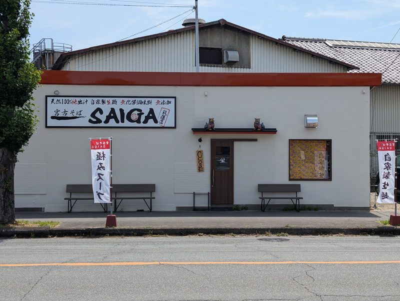 白い壁に「宮古そば SAIGA」の看板とのぼりが並ぶ店の外観