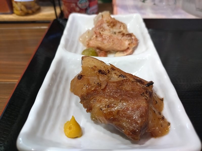 からしを添えて白い皿に盛った、煮込んだ豚肉